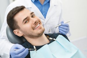 Shot of a cheerful handsome man smiling to the camera sitting in a dental chair his dentist preparing for dental checkup on the background copyspace health medicine people dentistry doctor curing