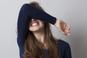 despair and anger concept - shocked young woman hiding her face with her arm,grinding teeth for dramatic resignation,studio shot