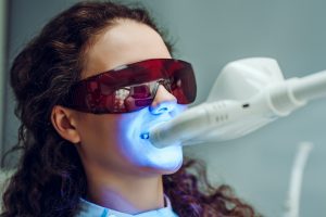 Girl patient in the dental clinic. Teeth whitening UV lamp with photopolymer composition.