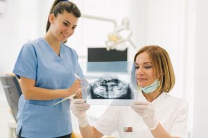 woman dentist with her assistant examine dental x-ray