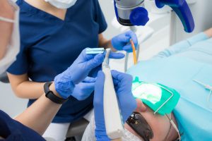 Macro photo of dental instruments: drill and needle for treating root canals and pulpitis in a dentist hand in a blue glove. The doctor measures the length of the needle with a special ruler