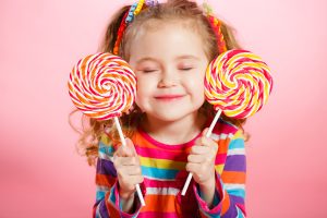 Studio portrait of a beautiful little girl with large Lollipop