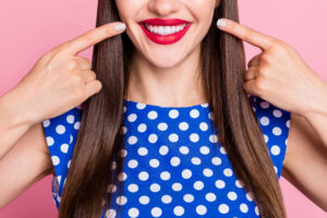 Cropped photo of young cheerful woman happy positive smile point fingers teeth ceramic white isolated over pink color background.