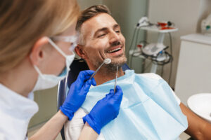 Image of a handsome happy young man sitting in medical dentist center.