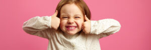 Funny shot of little girl with her thumbs up, cool smiling, portrait of happy child over pink background.