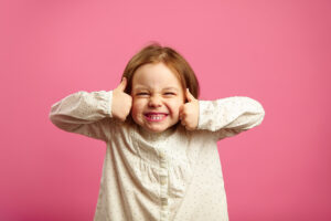 Funny shot of little girl with her thumbs up, cool smiling, portrait of happy child over pink background.