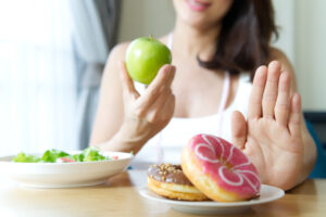 Woman rejecting junk food or unhealthy food such as donuts and c