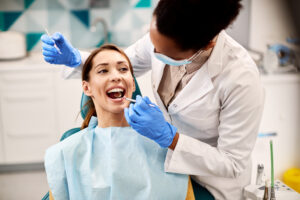 Young smiling woman having her teeth checked by dentist during appointment at dental clinic.